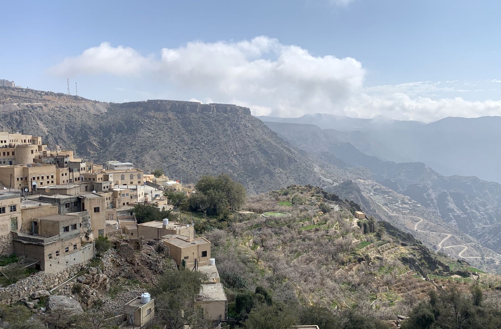 Von Weitem kaum als Hotelanlage zu erkennen – Oberhalb eines gewaltigen Canyons liegt das Anantara Al Jabal Al Akhdar Resort auf einem Plateau, behutsam in die Natur integriert (im Hintergrund), vorne das fast vollständig verlassene Bergdorf Ash Shirayjah