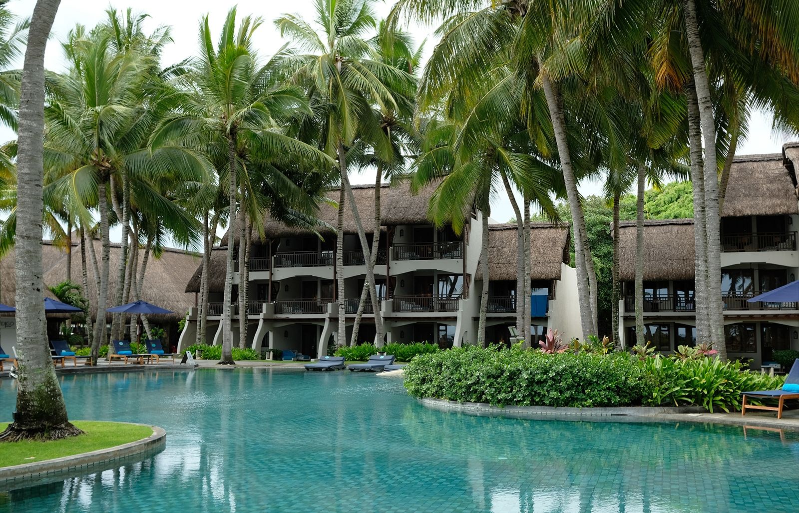 Vier große Swimming Pools bieten viel Platz zum Schwimmen und Entspannen unter Palmen   