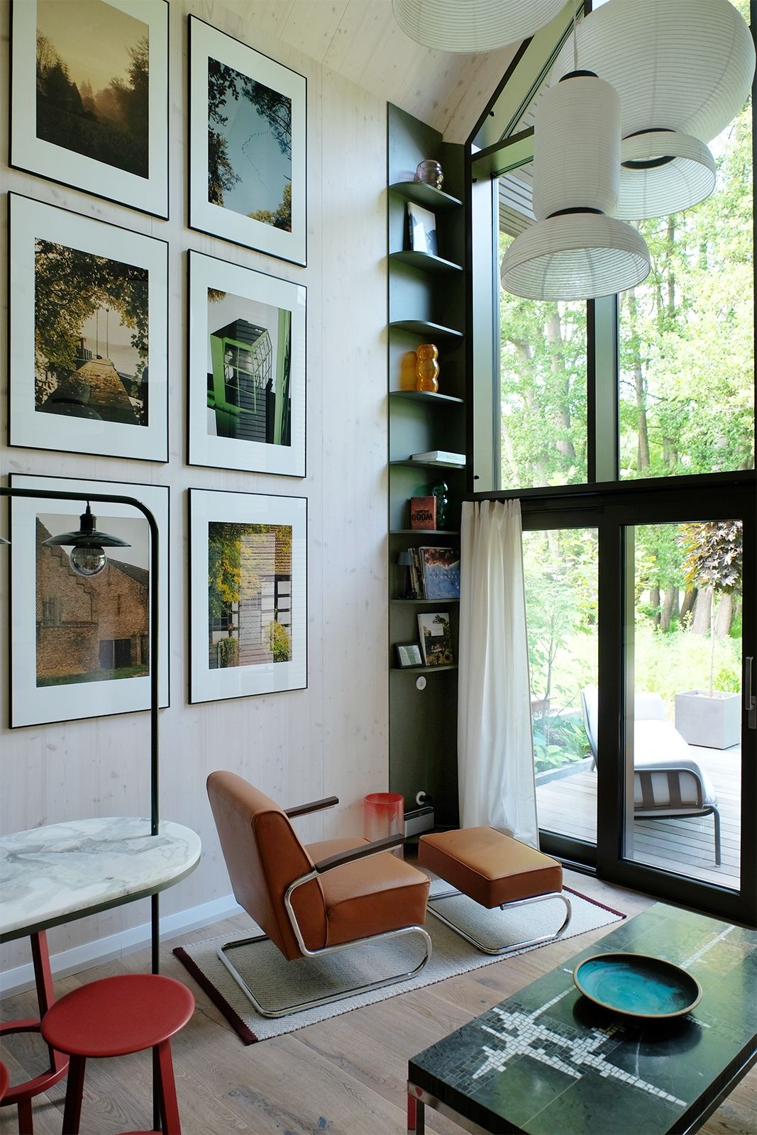 Wohnzimmer mit Ambiente & Ausblick: Im Vintage Thonet S 411 (in cognacfarbenem Leder neu bezogen) sitzen und Gedanken schweifen lassen, in Bildbänden schmökern oder am Küchentresen einen Snack genießen – Alles kann, nichts muss; Fotokunst mit Motiven aus der Umgebung der Chalets zu unterschiedlichen Jahreszeiten von PION Studio, Warschau; ausgewählte Vintage Möbel und Accessoires aus der privaten Sammlung von Piotr Wiśniewski