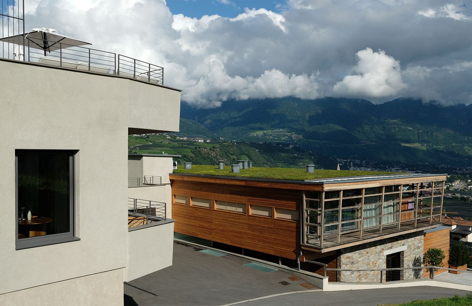 Gelungenes Ensemble – Zwei unterschiedliche Baustile, die sich gekonnt ergänzen: Architektur aus Holz und Glas von Matteo Thun (Pergola Residence) und Beton, horizontale Linien, klare Formensprache, Entwurf Thomas Kienzl (Spazio 46)