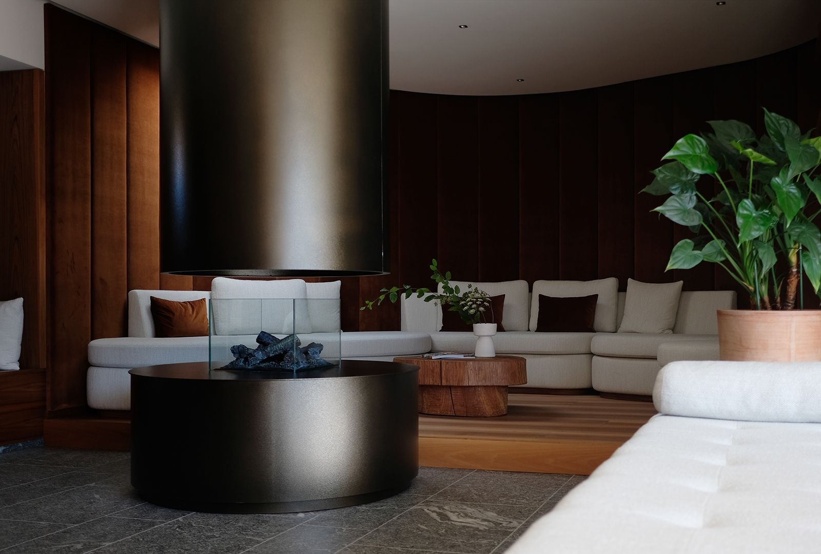 Gleich neben der Sauna befindet sich der Ruheraum, Design HPA; Kamin, gehämmerte Bronze; mit Samt bezogene Wand (Atelier Prinoth Textilwerkstatt), Stoff von Élitis; Sofa mit Bouclé-Stoff von Dedar s.o., Custom Design HPA; Beistelltisch aus Teakholz
