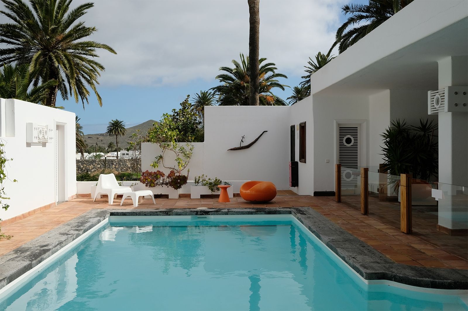 Pool mit Pastil Chair unter Palmen